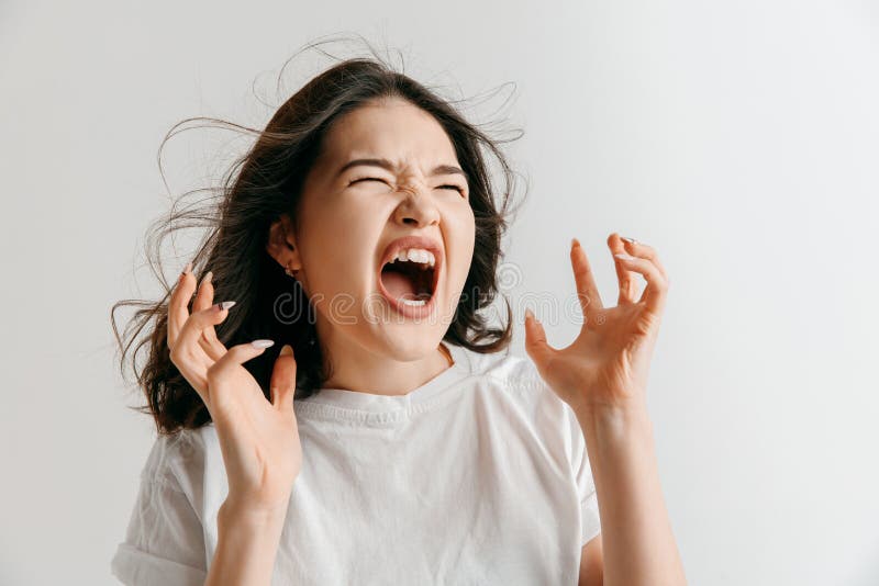 Screaming, hate, rage. Crying emotional angry asian woman screaming on gray studio background. Emotional, young face. Female half-length portrait. Human emotions, facial expression concept. Screaming, hate, rage. Crying emotional angry asian woman screaming on gray studio background. Emotional, young face. Female half-length portrait. Human emotions, facial expression concept.