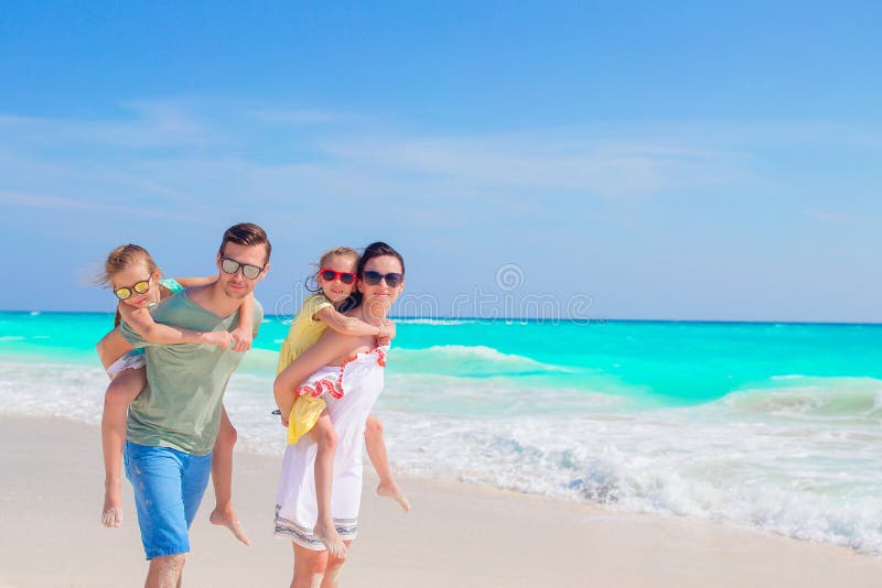 Den unga familjen på semester har mycket gyckel på stranden royaltyfri foto Den unga familjen på semester har mycket gyckel på stranden royaltyfri foto