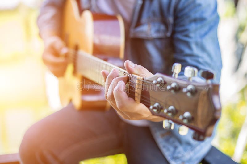 Den unga hipstermannen som spelar gitarren till att koppla av p? hans ferie, tycker om med naturlig och ny luft royaltyfria bilder Den unga hipstermannen som spelar gitarren till att koppla av p? hans ferie, tycker om med naturlig och ny luft royaltyfria bilder