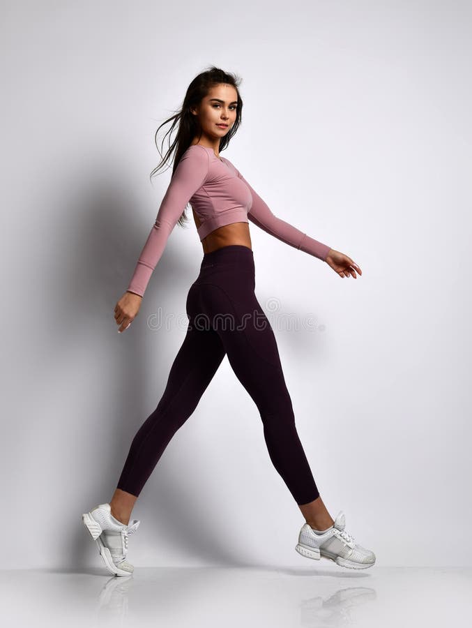 Den unga idrotts- kvinnabrunettflickan i en bra form i moderiktig sportswear som går i idrottshalllikformig, gör cardio övningar arkivbild Den unga idrotts- kvinnabrunettflickan i en bra form i moderiktig sportswear som går i idrottshalllikformig, gör cardio övningar arkivbild