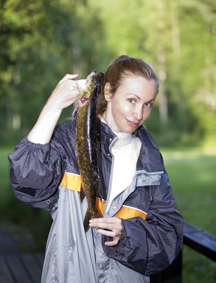 Den unga kvinnan fiskaren med den fångade piken royaltyfri fotografi Den unga kvinnan fiskaren med den fångade piken royaltyfri fotografi
