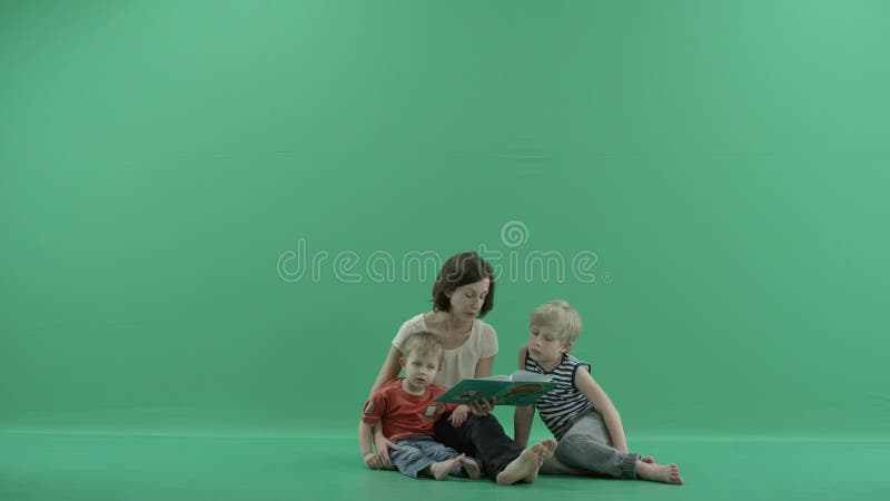 Den unga kvinnan läser en bok till barnen