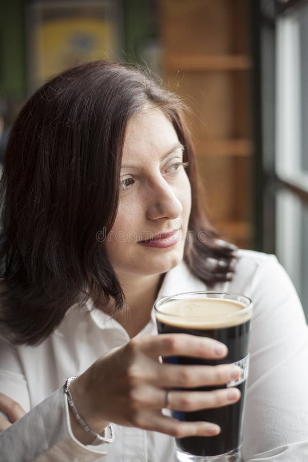 Den unga kvinnan med härlig brunt synar dricka en halv liter av kraftigt royaltyfri fotografi Den unga kvinnan med härlig brunt synar dricka en halv liter av kraftigt royaltyfri fotografi