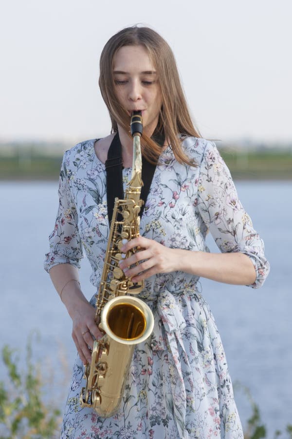 Den unga kvinnan med saxofonen i parkerar royaltyfria foton Den unga kvinnan med saxofonen i parkerar royaltyfria foton