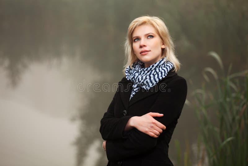 Den unga kvinnan mot ett dimmigt landskap royaltyfri fotografi Den unga kvinnan mot ett dimmigt landskap royaltyfri fotografi