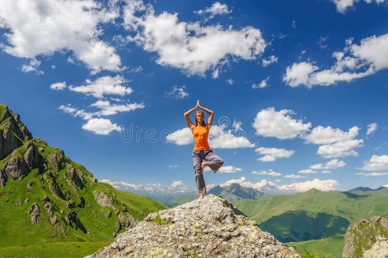 Den unga kvinnan övar yoga i bergen arkivbild Den unga kvinnan övar yoga i bergen arkivbild