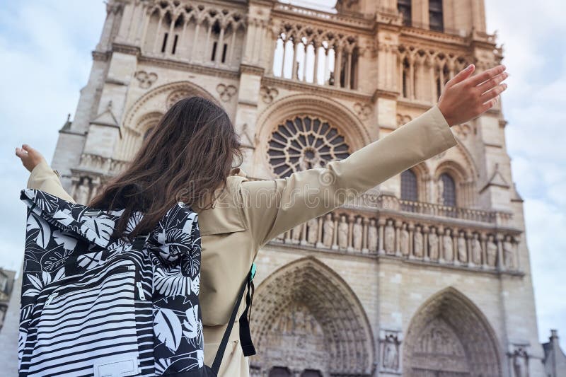 Den unga lyckliga kvinnan som framme står av den berömda Notre Dame domkyrkan i Paris, händer lyftte upp till himlen royaltyfria foton Den unga lyckliga kvinnan som framme står av den berömda Notre Dame domkyrkan i Paris, händer lyftte upp till himlen royaltyfria foton