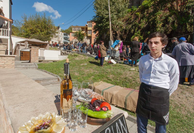 Den unga mannen inviterar turister för att smaka Chacha, traditionell alkoholdryck royaltyfria foton Den unga mannen inviterar turister för att smaka Chacha, traditionell alkoholdryck royaltyfria foton
