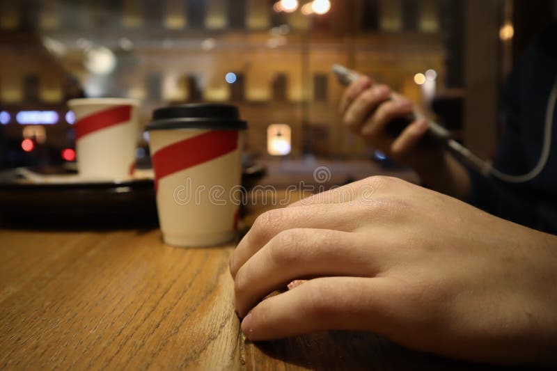 Den unga mannen sitter i ett kafé och läser meddelanden i telefonen arkivbild Den unga mannen sitter i ett kafé och läser meddelanden i telefonen arkivbild