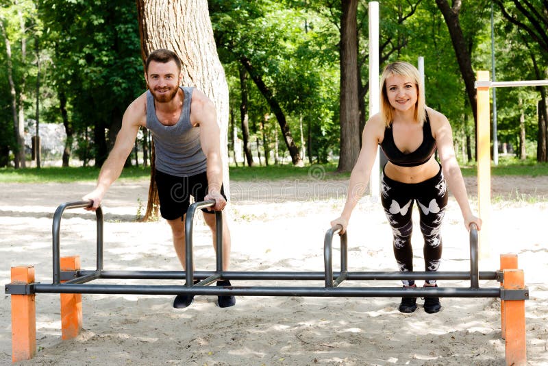 Den unga sportive kvinnan och skäggiga mannen som gör push-UPS, övar in royaltyfria foton Den unga sportive kvinnan och skäggiga mannen som gör push-UPS, övar in royaltyfria foton