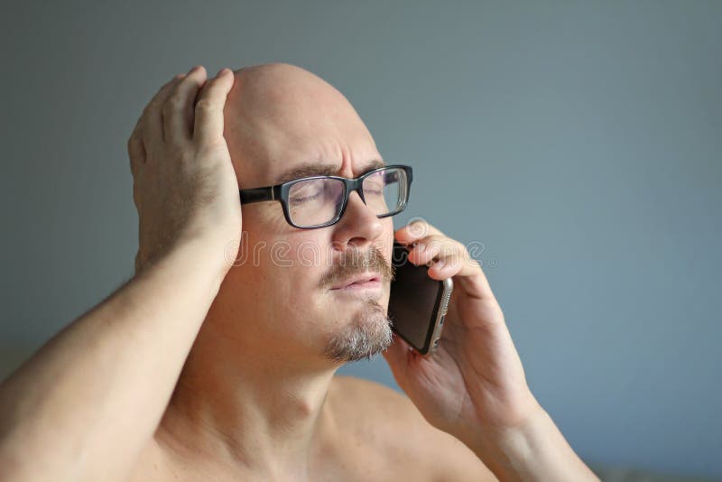 Den unga stiliga mannen i svarta exponeringsglas talar på telefonen och förvånas Stora problem, dåliga nyheter closeup isolerad m royaltyfri foto Den unga stiliga mannen i svarta exponeringsglas talar på telefonen och förvånas Stora problem, dåliga nyheter closeup isolerad m royaltyfri foto