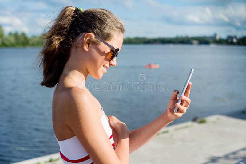 Den unga tonårs- flickan skjuter videoen på en smartphone för hennes kanal På en solig sommardag i staden parkera arkivbilder Den unga tonårs- flickan skjuter videoen på en smartphone för hennes kanal På en solig sommardag i staden parkera arkivbilder