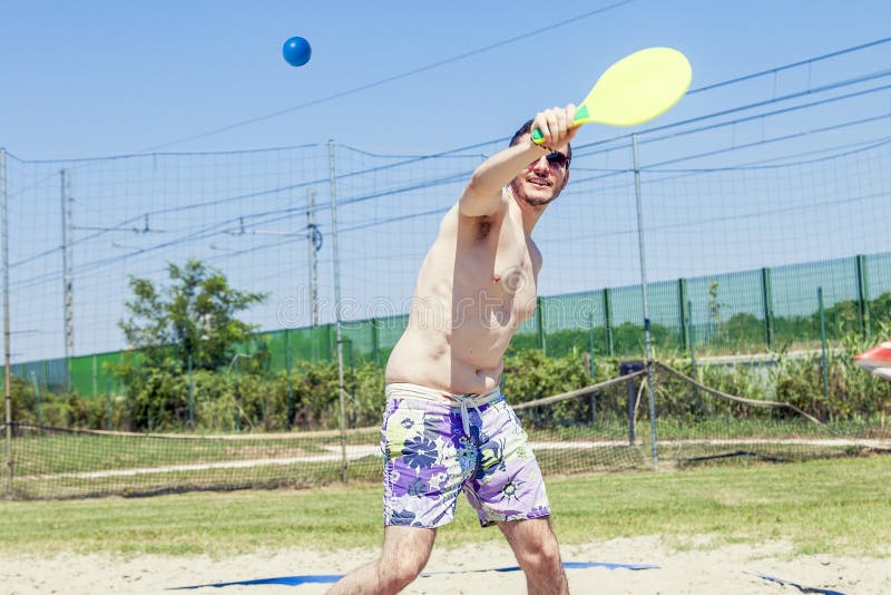 Den unga vuxna mannen spelar tennis på stranden royaltyfria foton Den unga vuxna mannen spelar tennis på stranden royaltyfria foton