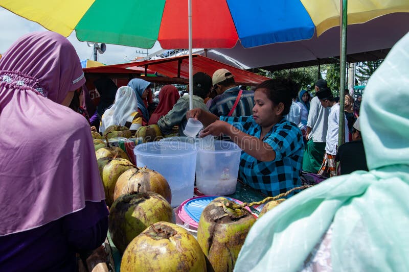 Pasuruan, Indonesia - January 11th, 2014 : a seller of young coconut ice is serving buyers in the busy center of the city at the Pasuruan City anniversary event. Pasuruan, Indonesia - January 11th, 2014 : a seller of young coconut ice is serving buyers in the busy center of the city at the Pasuruan City anniversary event