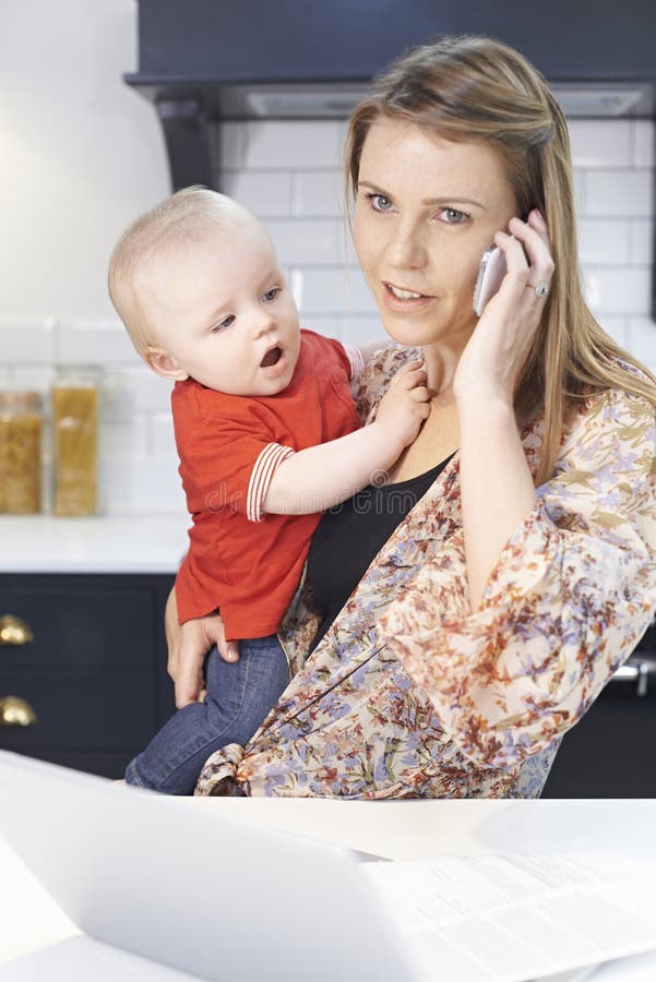 Den upptagna modern med behandla som ett barn att klara av med den hemmastadda stressiga dagen royaltyfri fotografi Den upptagna modern med behandla som ett barn att klara av med den hemmastadda stressiga dagen royaltyfri fotografi