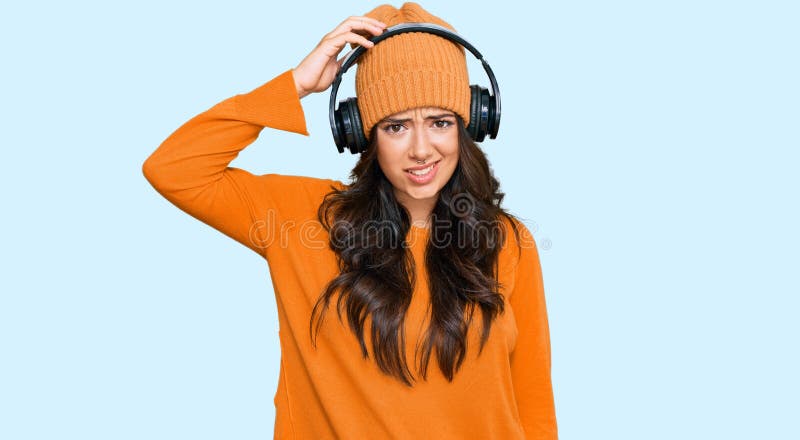 Den Vackra Brunette-unga Kvinnan Som Lyssnar På Musik Med Hörlurar  Förvirrar Och Undrar över Frågan Fotografering för Bildbyråer - Bild av  attraktiv, framsida: 219545509