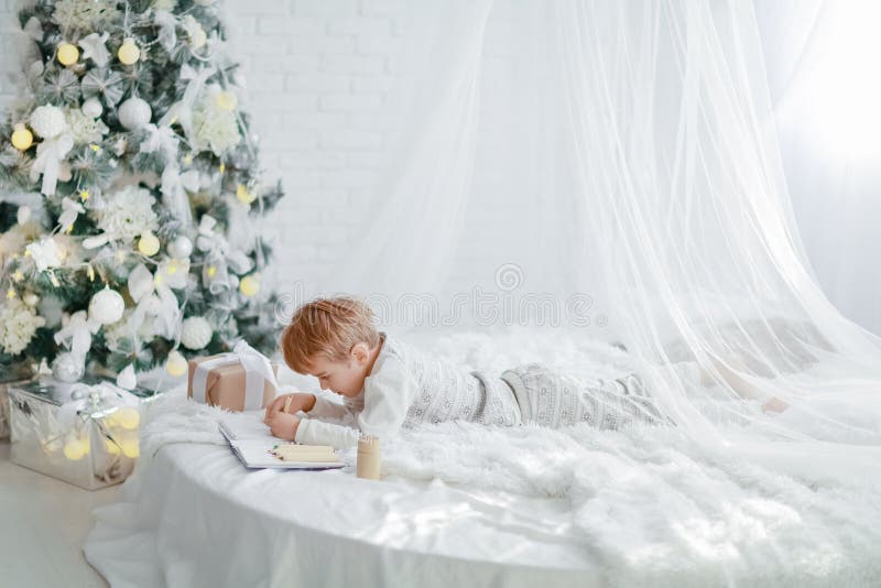 Den vackra lilla babypojken i pyjamas med stjärnor firar jul. nya års semester. barnlek i vitt royaltyfri fotografi