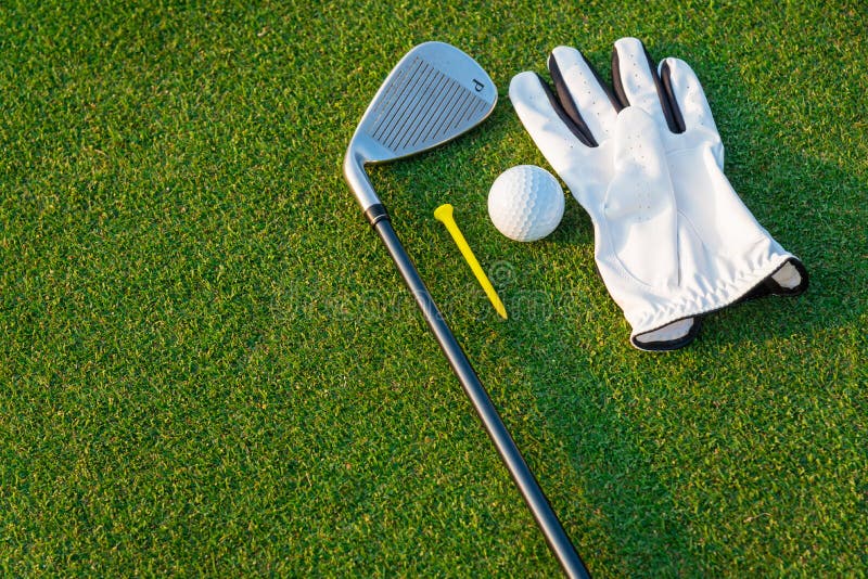 Den vita handsken för golfsportutrustning, golfbollen, golfklubben och den gula utslagsplatsgolfen med grönt gräs royaltyfri foto Den vita handsken för golfsportutrustning, golfbollen, golfklubben och den gula utslagsplatsgolfen med grönt gräs royaltyfri foto