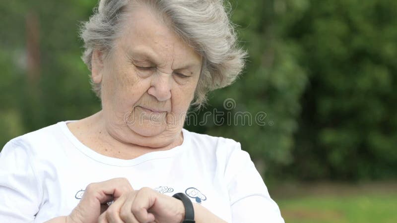 Den äldre kvinnan ser en armbandkonditionbogserare