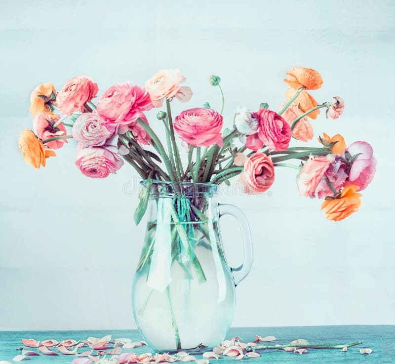 Den älskvärda buketten av den härliga ranunculusen blommar i den glass vasen på tabellen på ljus - blå turkosbakgrund arkivbild