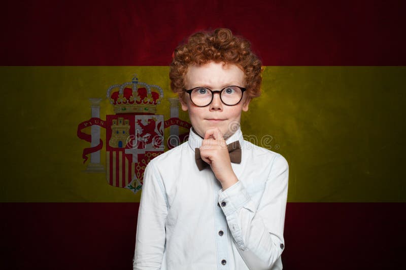 Denkende Kinderjunge in Schuluniform auf spanischer Flagge Hintergrund. Konzept Bildung und Kindheit in Spanien lizenzfreies stockbild