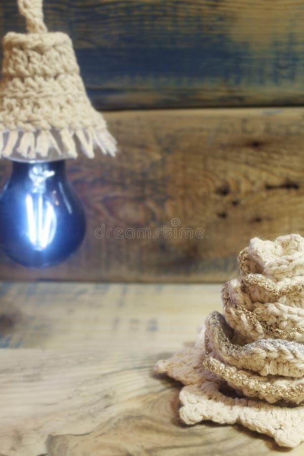 The blue magic scene on the grinded, ground, structured wooden background. Light bulb with a crochet shade. The blue magic scene on the grinded, ground, structured wooden background. Light bulb with a crochet shade.