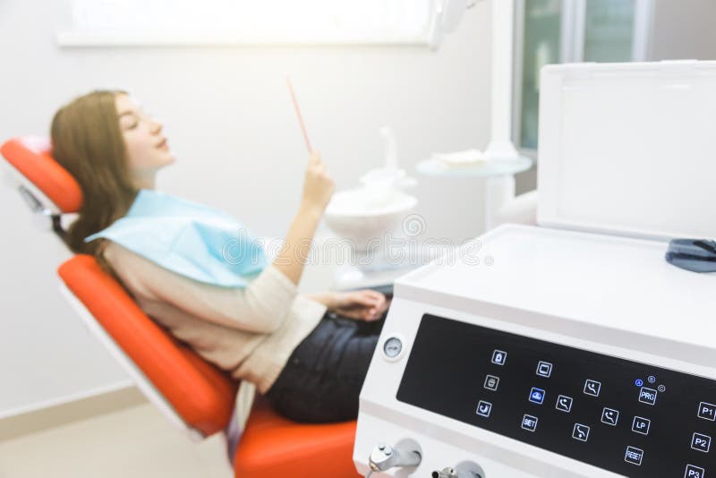 Dental clinic. Reception, examination of the patient. Teeth care. Young girl smiling, looking in the mirror after a royalty free stock images Dental clinic. Reception, examination of the patient. Teeth care. Young girl smiling, looking in the mirror after a royalty free stock images