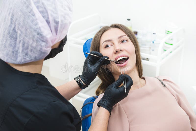 Dental clinic. Reception, examination of the patient. Teeth care. Young woman undergoes a dental examination by a royalty free stock image Dental clinic. Reception, examination of the patient. Teeth care. Young woman undergoes a dental examination by a royalty free stock image