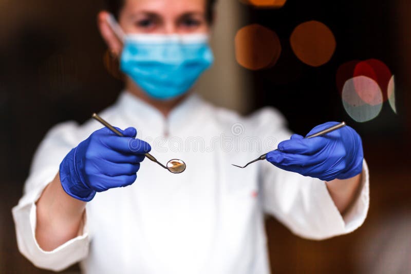 Dental and endodontic instruments in hands of dentist. The dentist women in blue gloves holding metal professional tools stock images Dental and endodontic instruments in hands of dentist. The dentist women in blue gloves holding metal professional tools stock images