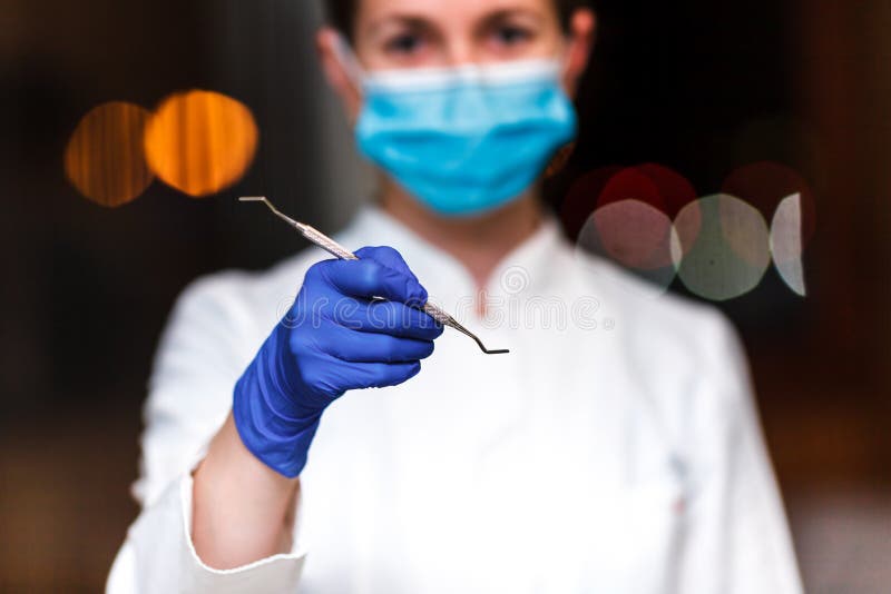 Dental and endodontic instruments in hands of dentist. The dentist women in blue gloves holding metal professional tools royalty free stock image Dental and endodontic instruments in hands of dentist. The dentist women in blue gloves holding metal professional tools royalty free stock image