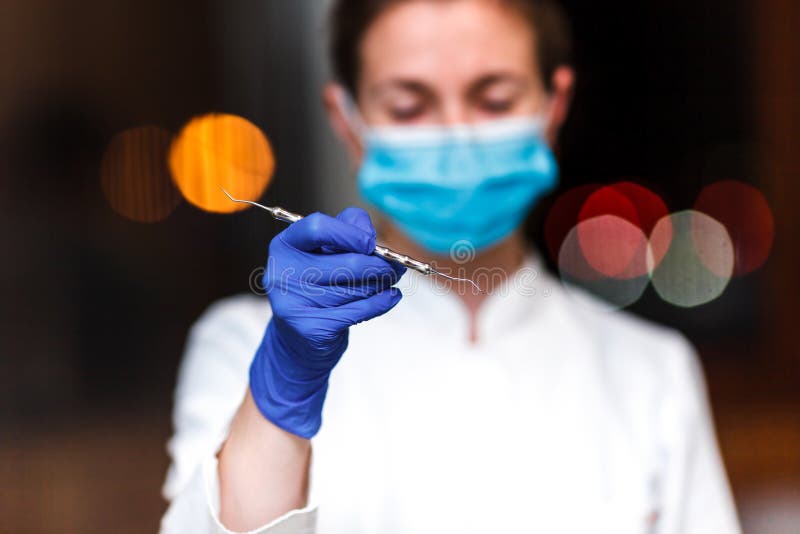 Dental and endodontic instruments in hands of dentist. The dentist women in blue gloves holding metal professional tools stock image Dental and endodontic instruments in hands of dentist. The dentist women in blue gloves holding metal professional tools stock image