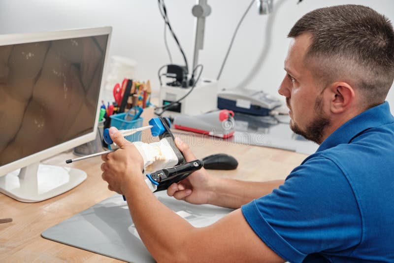 Dental Technician Producing Dental Prosthesis Under the Microscope