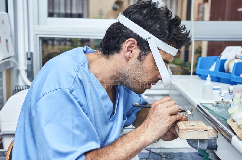 Dental Technician Working with Ceramic Dental Implants with Magnifying