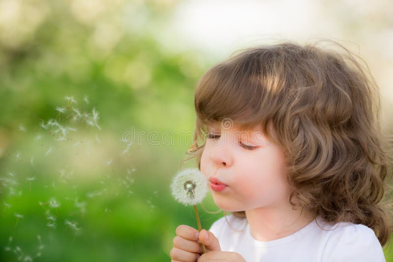 Dente di leone di salto del bambino felice fotografia stock libera da diritti Dente di leone di salto del bambino felice fotografia stock libera da diritti
