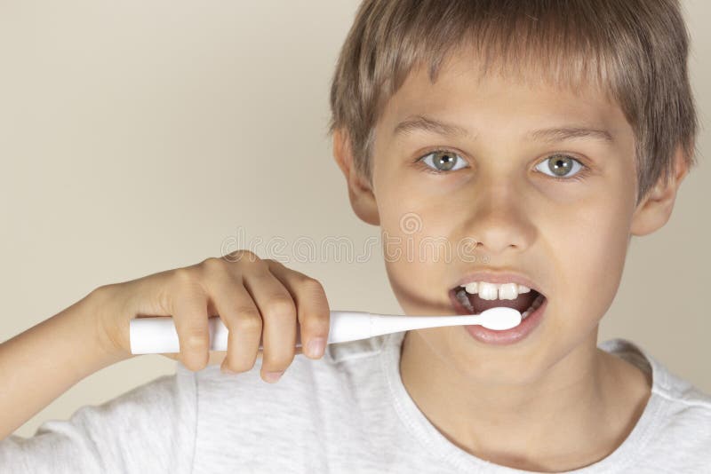 Denti di spazzolatura del bambino con lo spazzolino da denti elettrico bianco fotografia stock libera da diritti Denti di spazzolatura del bambino con lo spazzolino da denti elettrico bianco fotografia stock libera da diritti
