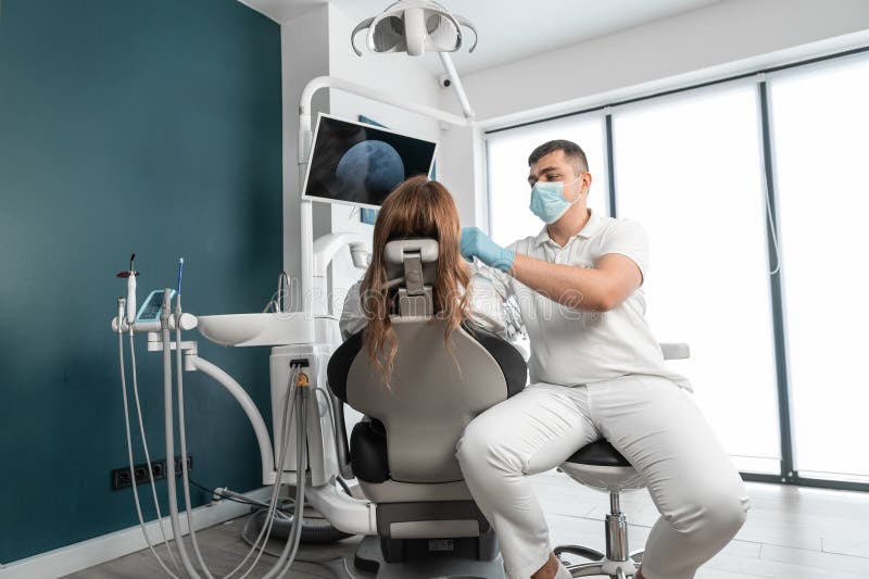 Dentistul analizează cu atenție starea dintelui pacienților și a cavității bucale. centrul medical furnizează stock image