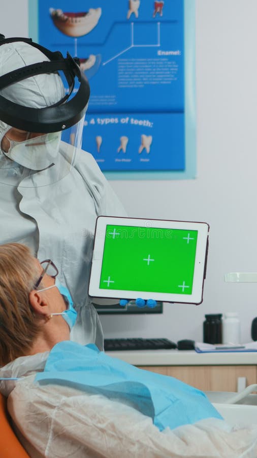Dentist with Face Shield Pointing at Green Screen Display Stock Photo