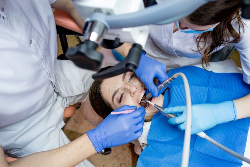 Dentist Looking through a Microscope at the Patient& X27;s Teeth