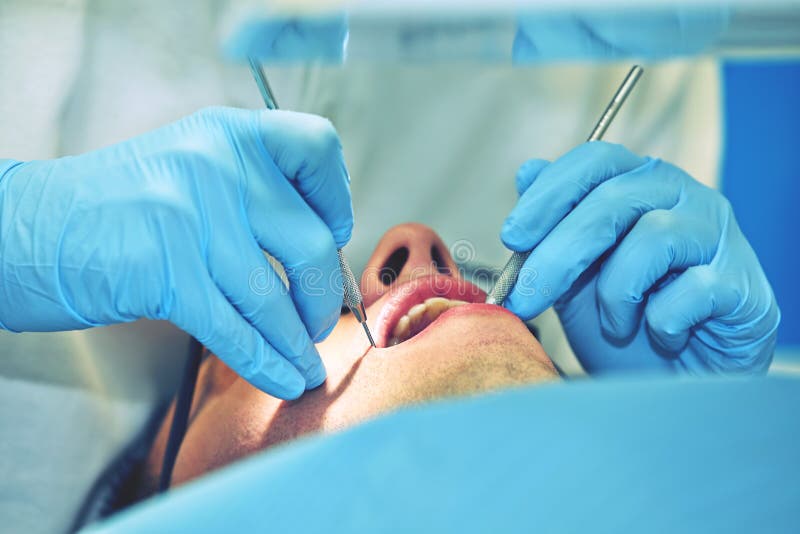 Dentist Preparing for the Medical Examination with Young Woman Patient Wearing Medical Gloves in