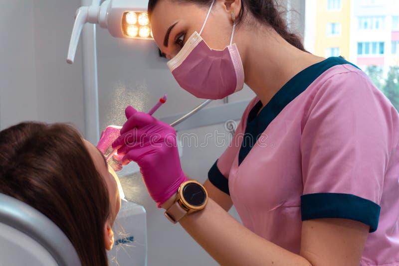 Dentist in Pink Uniform Treat the Teeth of a Patient Stock Photo