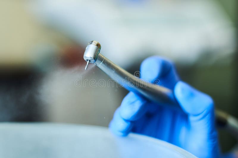Dentist`s Hands with Blue Gloves Working with Dental Drill in Dental