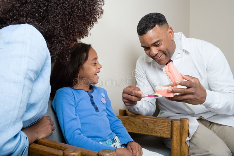 Dentist showing patient how to clean teeth stock image