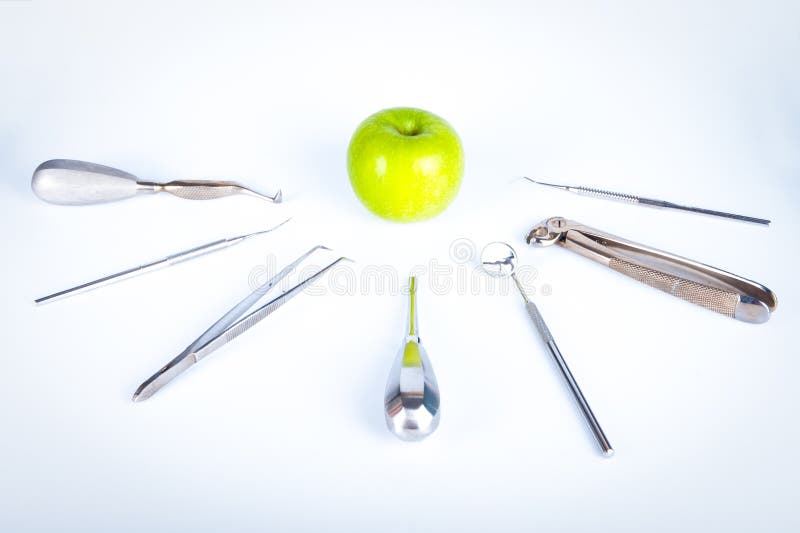 Dentist tools in front of green apple