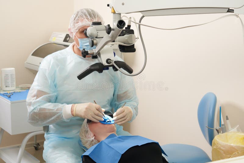 Dentist Working with Dental Microscope and Patient at Modern Dentist
