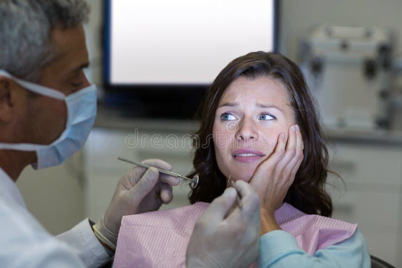 Dentista che esamina un paziente femminile con gli strumenti fotografia stock Dentista che esamina un paziente femminile con gli strumenti fotografia stock