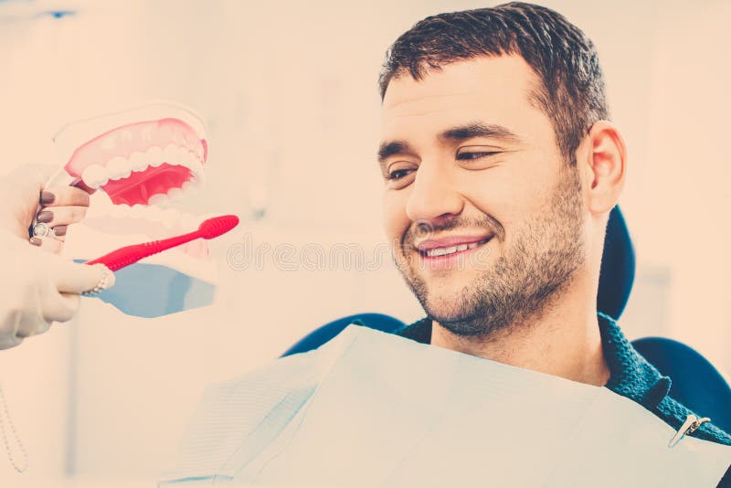 Dentista che mostra al paziente dell'uomo come pulire i denti fotografia stock libera da diritti Dentista che mostra al paziente dell'uomo come pulire i denti fotografia stock libera da diritti