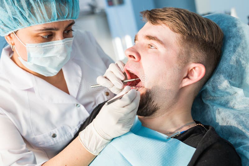 Dentista de la mujer en la oficina dental médica Ella es cura al paciente foto de archivo libre de regalías Dentista de la mujer en la oficina dental médica Ella es cura al paciente foto de archivo libre de regalías