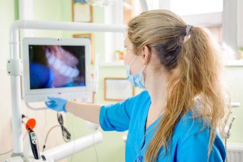 Dentista della donna che esamina l'immagine in tensione dei denti fotografia stock libera da diritti Dentista della donna che esamina l'immagine in tensione dei denti fotografia stock libera da diritti