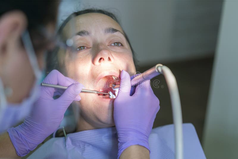 Dentista e paziente nell'ufficio del dentista Primo piano di uso della fresa per i denti pazienti nell'ufficio di odontoiatria in fotografia stock Dentista e paziente nell'ufficio del dentista Primo piano di uso della fresa per i denti pazienti nell'ufficio di odontoiatria in fotografia stock