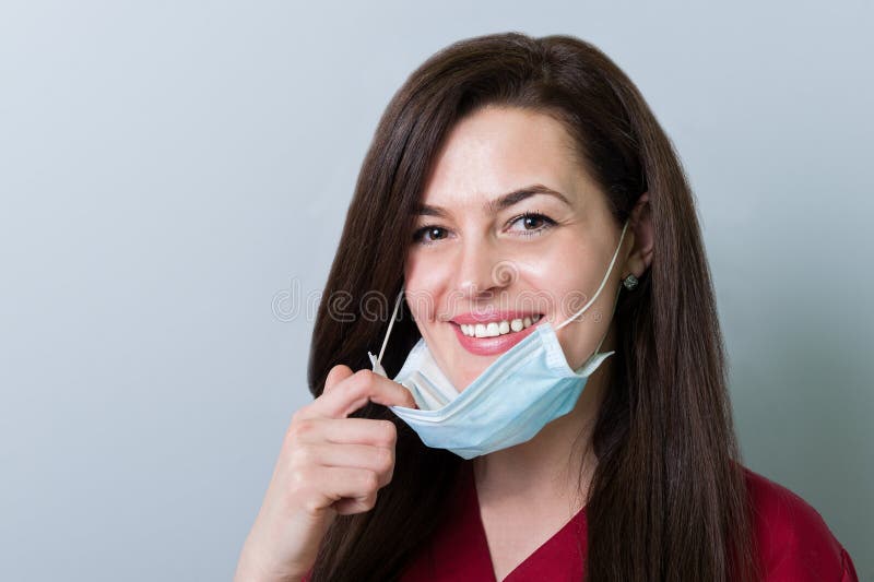Dentista fêmea bonito que remove a máscara e o sorriso fotografia de stock Dentista fêmea bonito que remove a máscara e o sorriso fotografia de stock